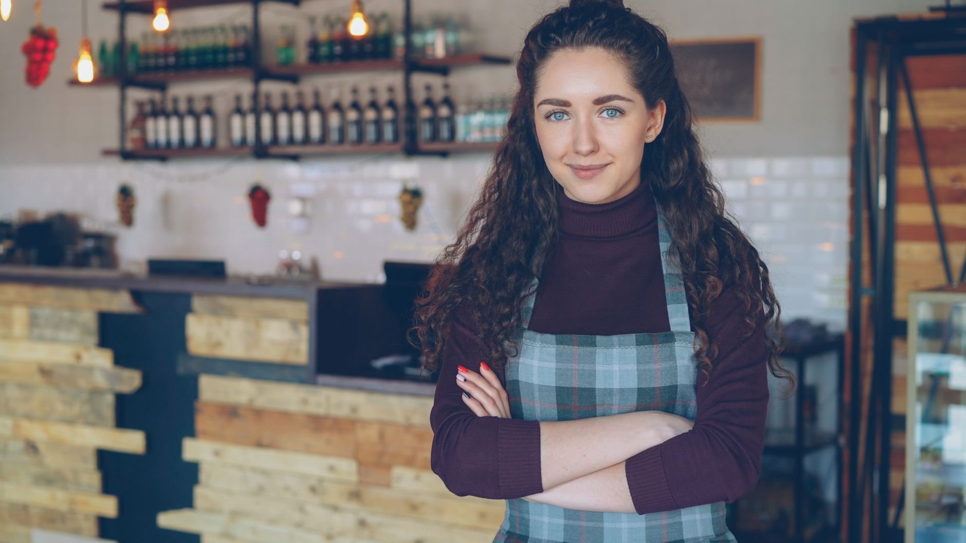 A confident café owner standing with arms crossed inside their shop